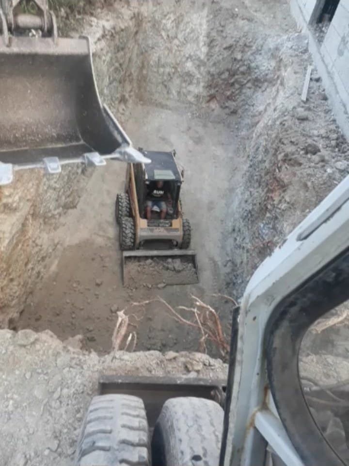 Μικρό ερπυστριοφόρο μηχάνημα δουλεύει μέσα σε βαθύ σκάμμα